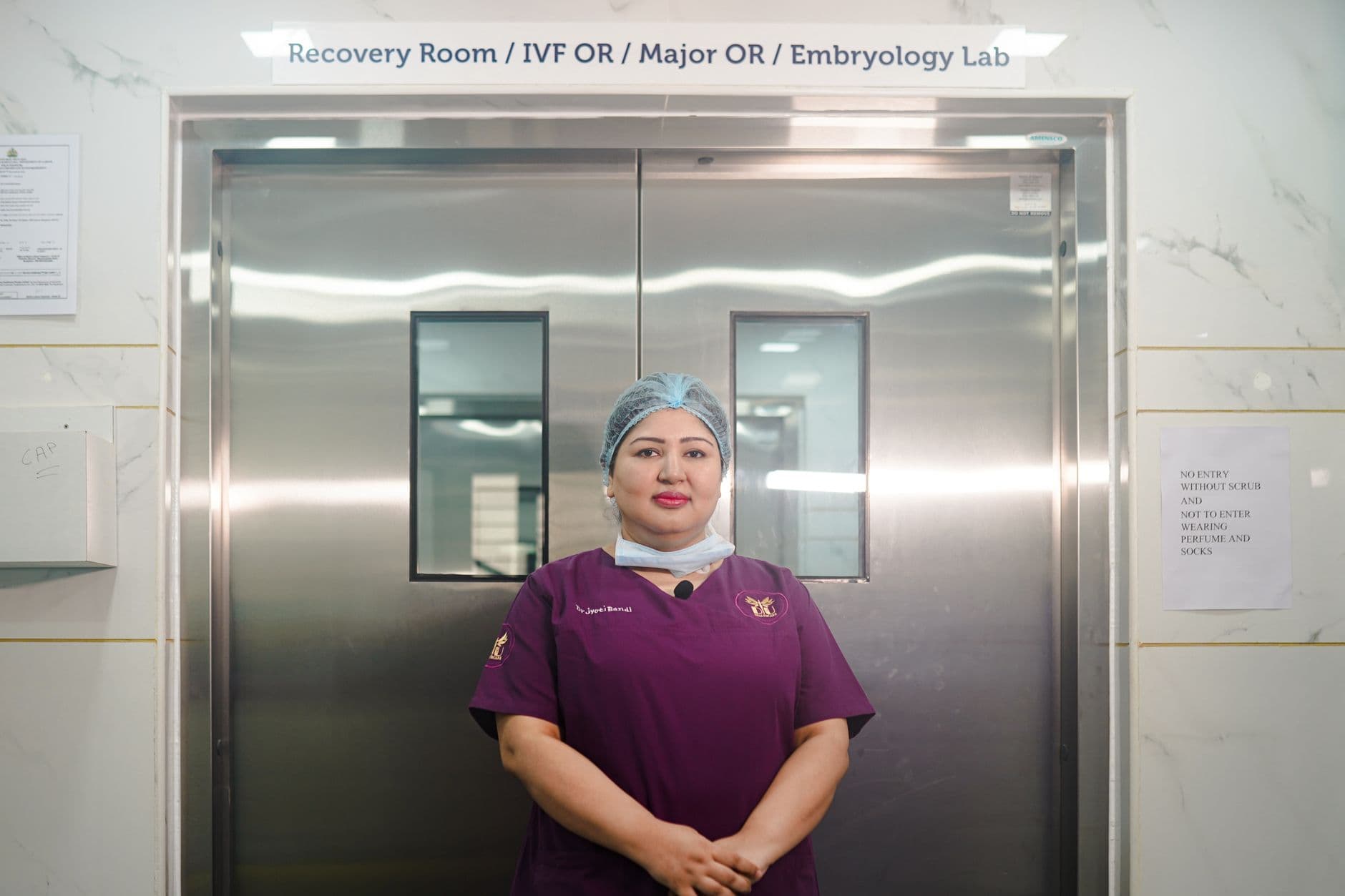 A healthcare professional standing in a hospital corridor in front of the recovery room and IVF lab.
