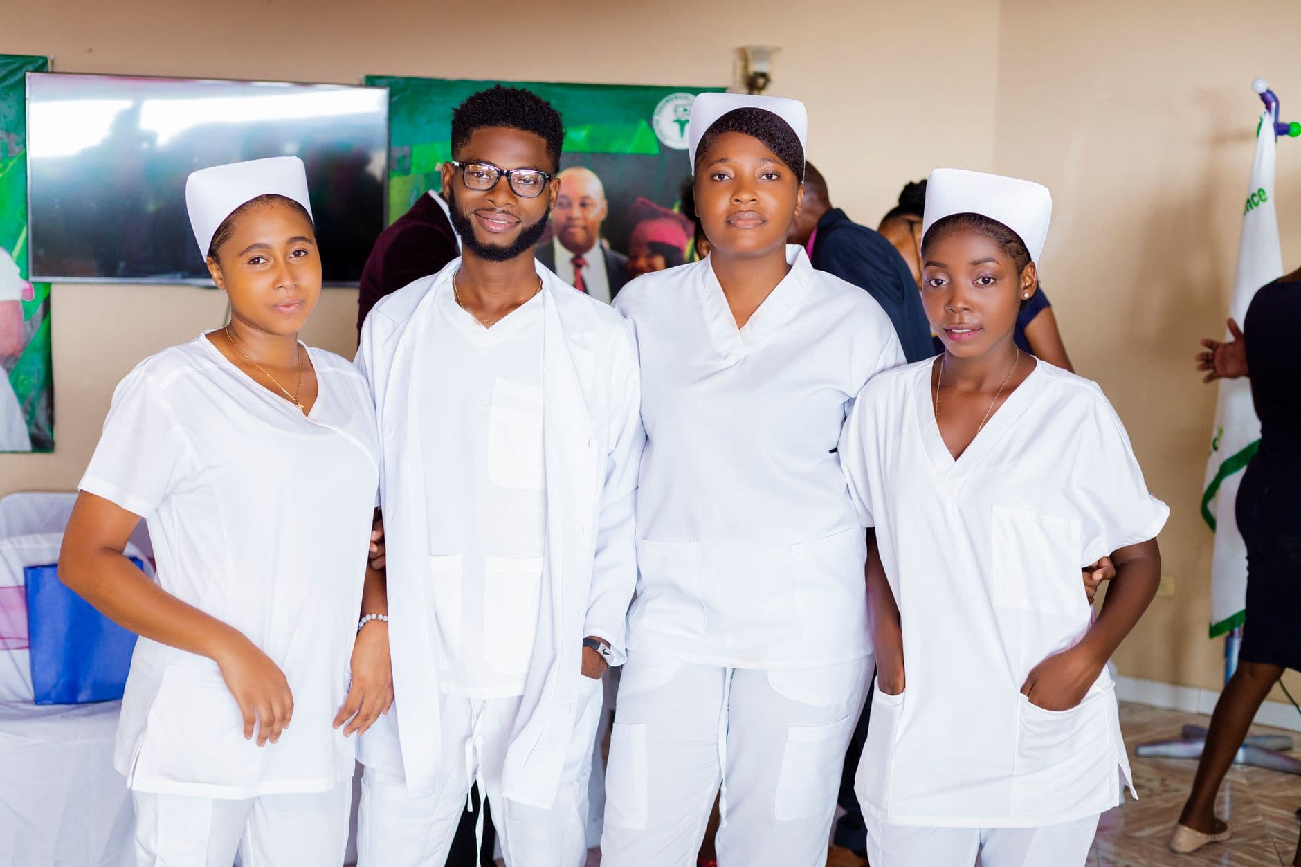 Four healthcare professionals wearing white uniforms, posing indoors.